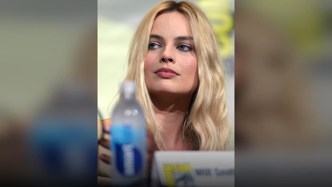 Margot Robbie smiling at a glamorous Hollywood premiere.
