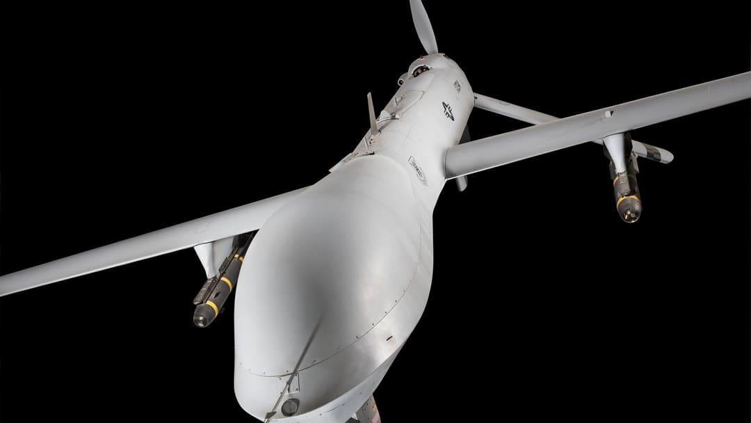 High-altitude unmanned military drone in flight against an open blue sky.