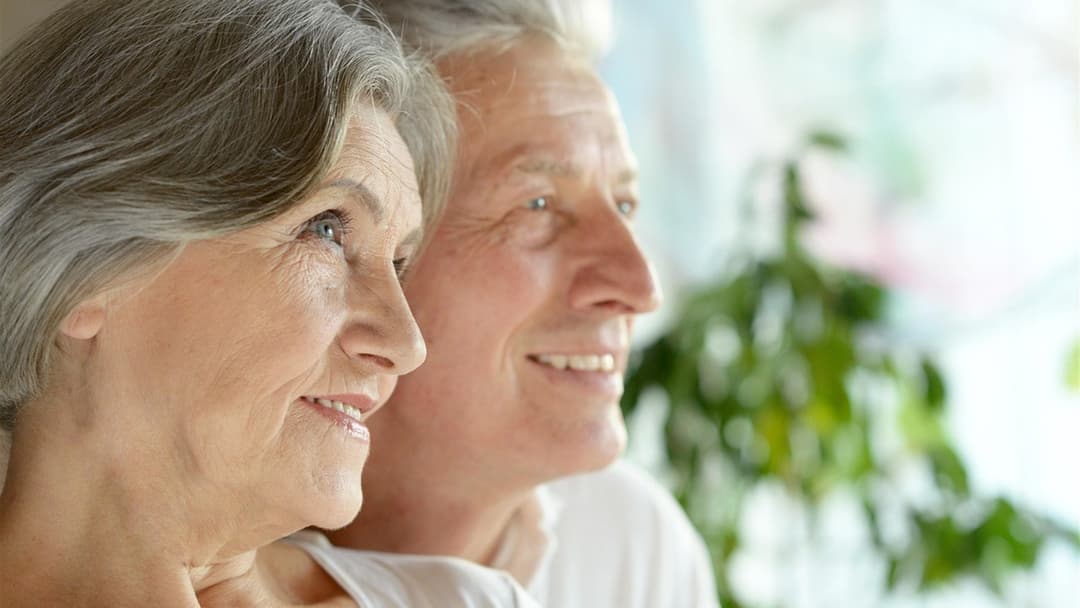 Close-up side profile of an older couple with matching smile lines around their eyes and mouths