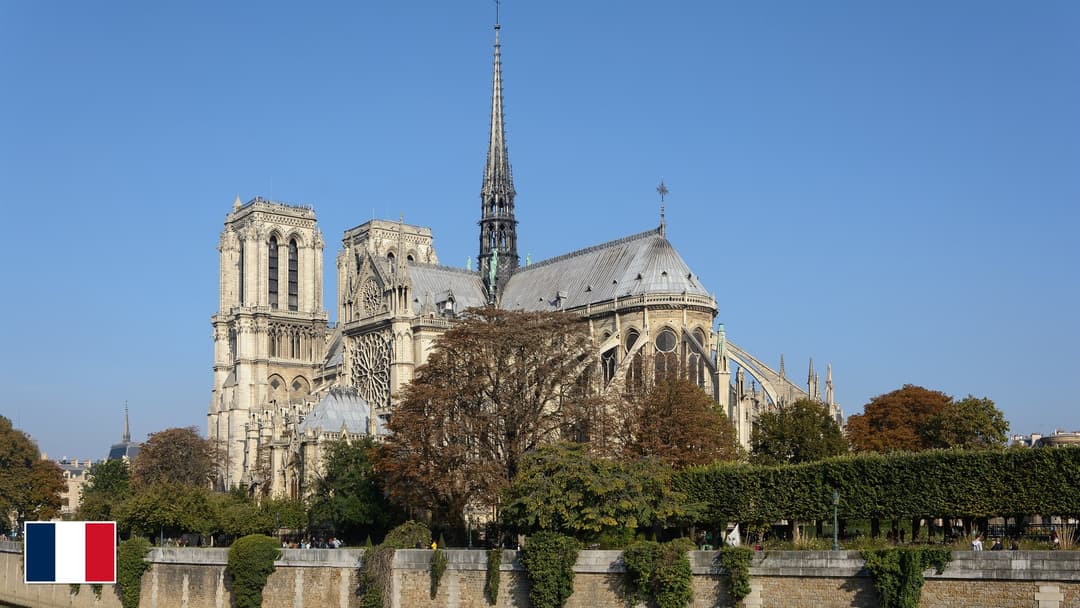 Notre-Dame de Paris flying buttresses and spire across the Seine River with flag of France in bottom-left corner