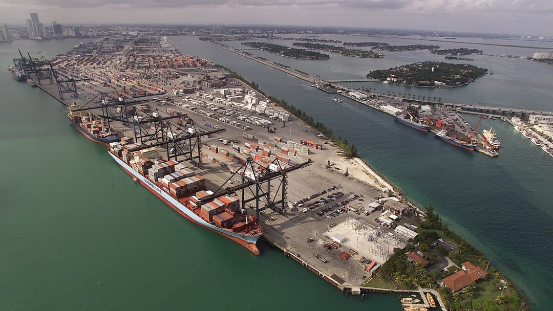 Aerial view of a major commercial cargo container shipping terminal and port cranes.