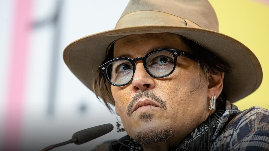 Johnny Depp in a fedora hat at a film festival premiere.