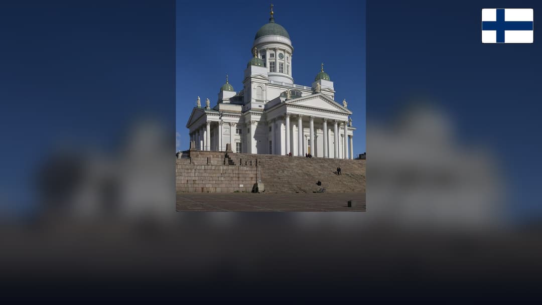 Helsinki Cathedral in Senate Square with the Finnish flag in the top right corner.