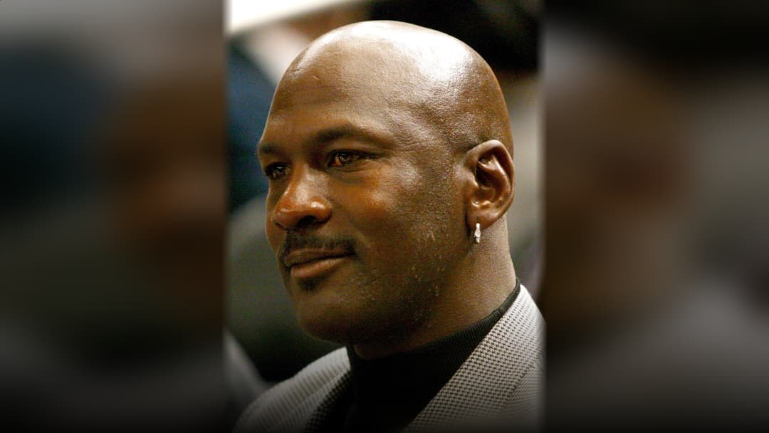 Basketball legend Michael Jordan smiling in a crisp suit portrait.