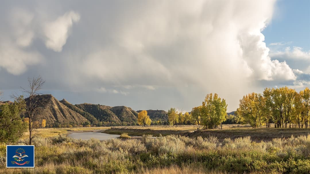 Little Missouri River canyon in Theodore Roosevelt National Park, North Dakota with the North Dakota state flag in the bottom left corner