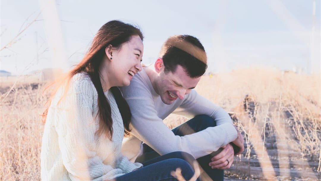 Couple laughing outdoors and mirroring each other's joyful facial expressions