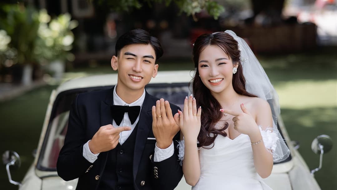 Bride and groom performing identical mirror-image hand gestures and smiles side by side