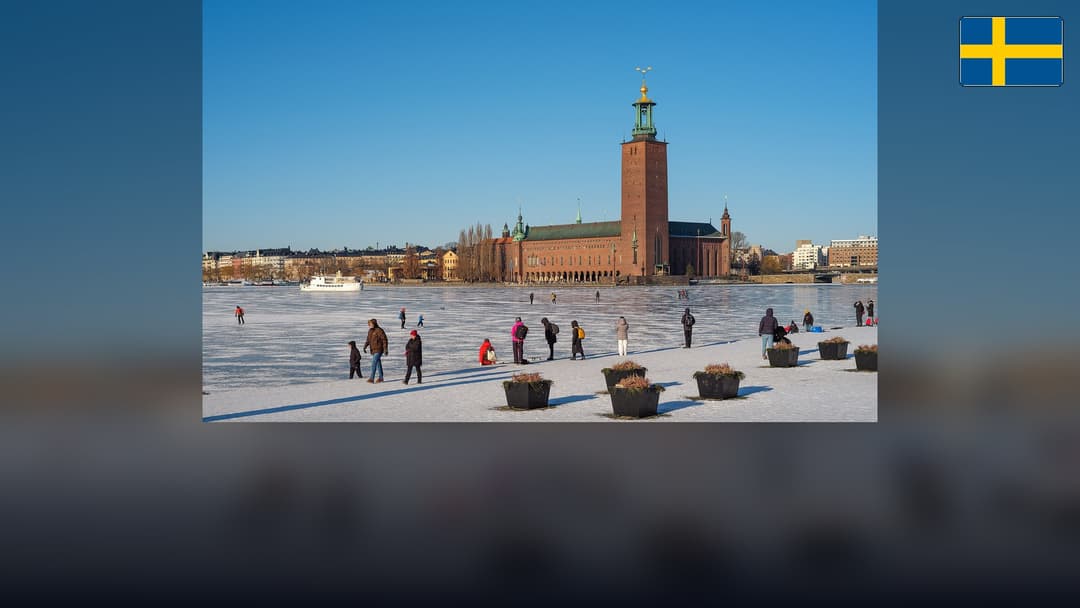 Stockholm City Hall across Riddarfjärden with the Swedish flag in the top right corner.