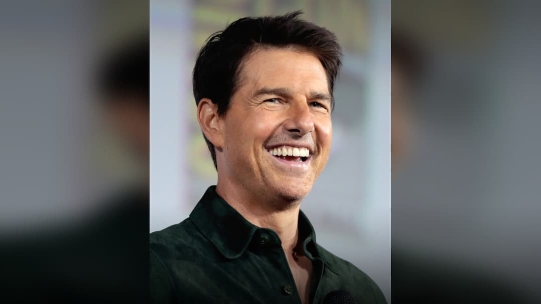 Tom Cruise smiling at a Comic-Con panel.