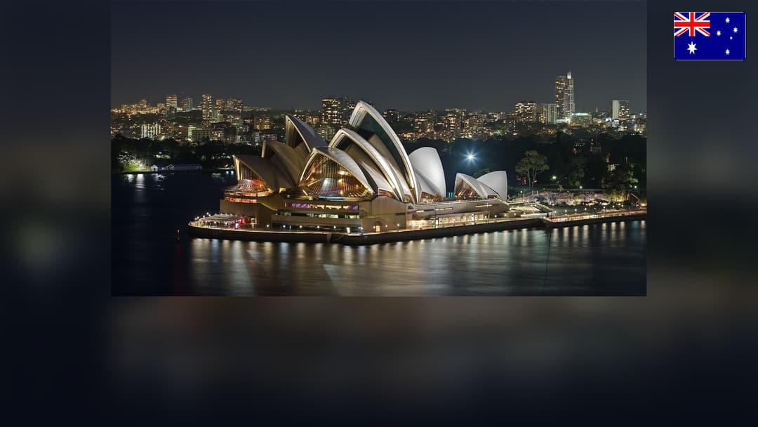 Sydney Opera House in Sydney Harbour with the Australian flag in the top right corner.