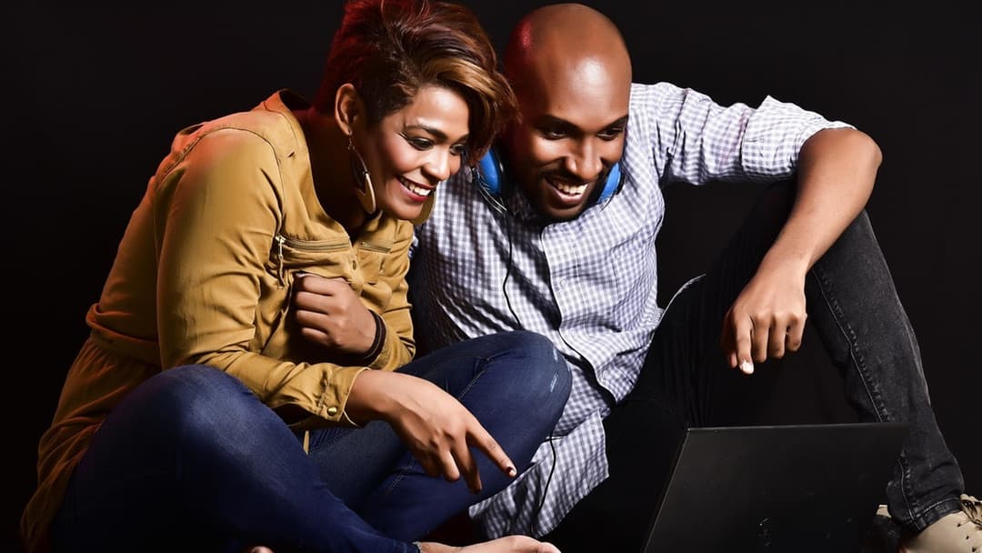 Cheerful couple sitting together and sharing an identical upbeat expression and demeanor