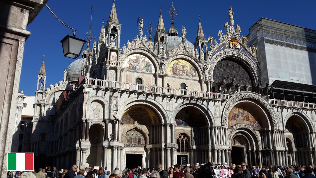 St. Mark's Basilica golden mosaics and domes in Venice with flag of Italy in bottom-left corner