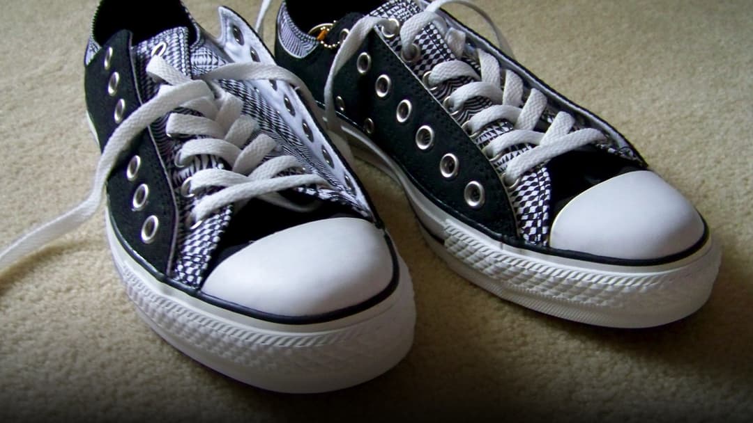 A pair of street sneakers placed directly on residential indoor carpeting.