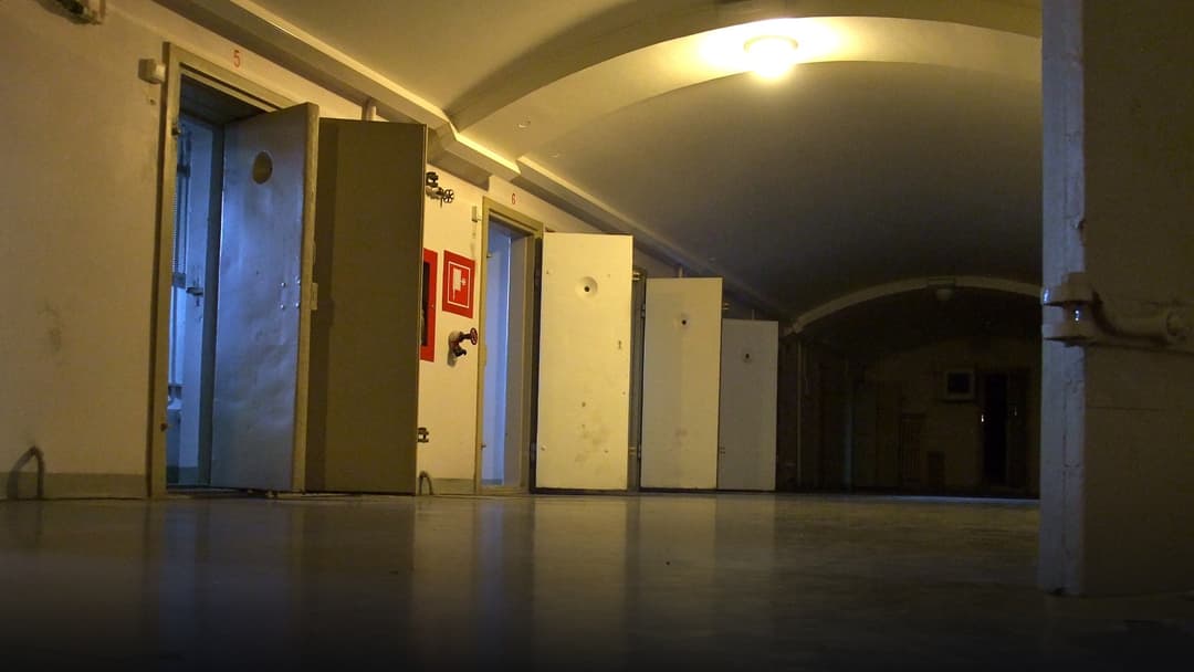 Long corridor of reinforced solitary confinement cell doors inside a maximum-security prison.