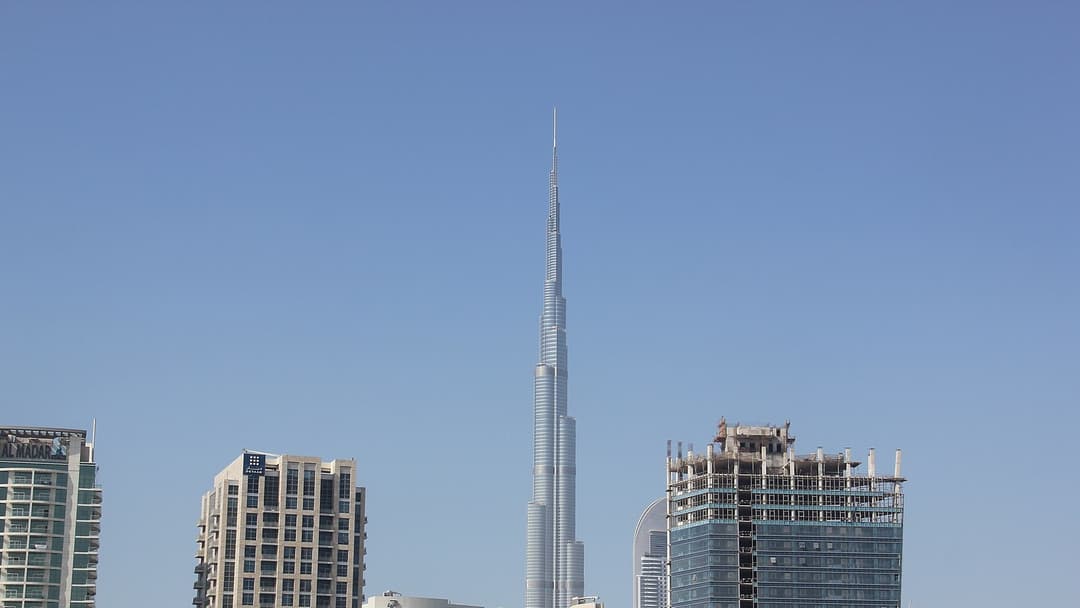 The gleaming spire of Burj Khalifa soaring into a clear blue sky above Downtown Dubai.