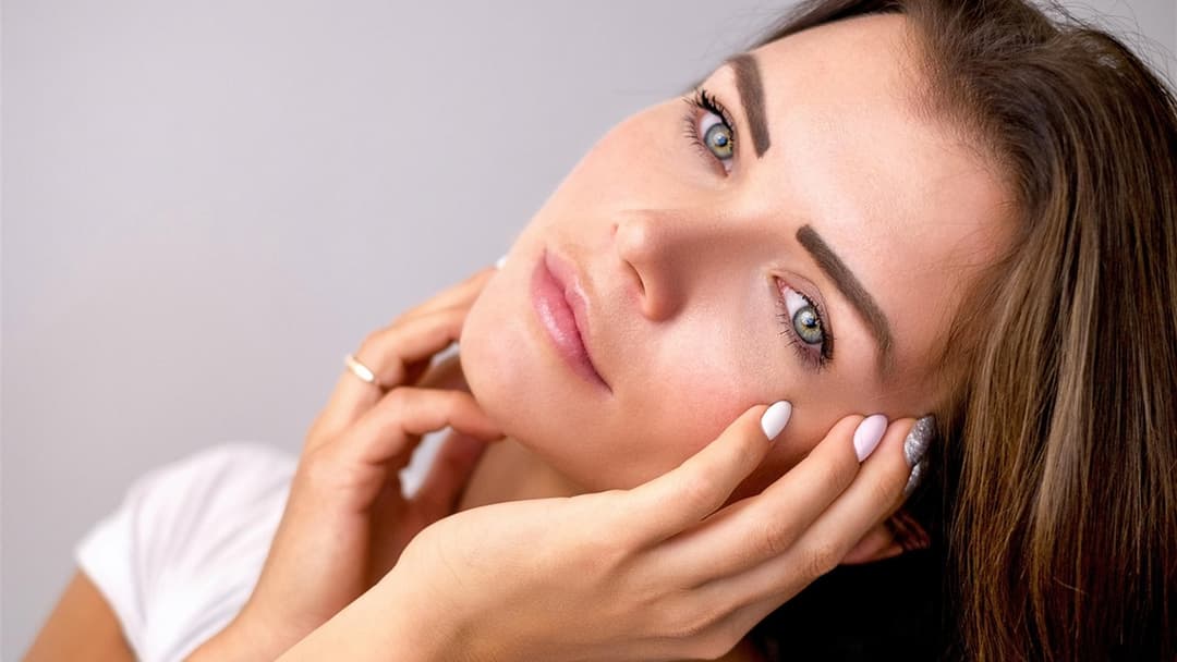 Close-up portrait of a woman with smooth, healthy skin in soft studio light.
