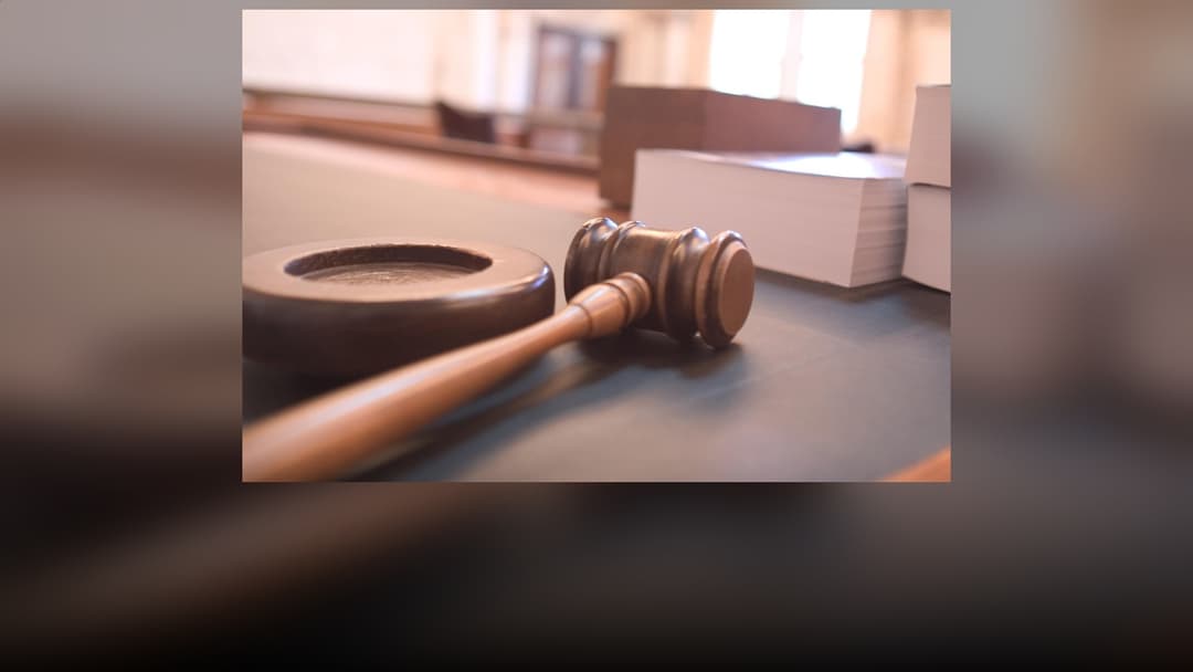 A wooden judicial gavel and sound block on a legal bench.