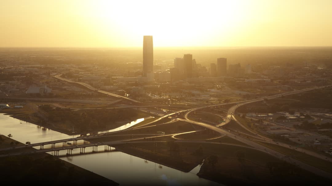 A breathtaking panoramic sunset view of the downtown Oklahoma City skyline reflected over the Oklahoma River.