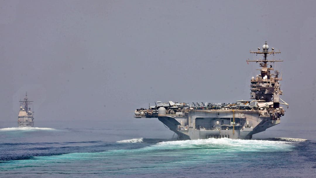 Aircraft carrier USS Abraham Lincoln and cruiser USS Cape St. George steaming single-file through the Strait of Hormuz.