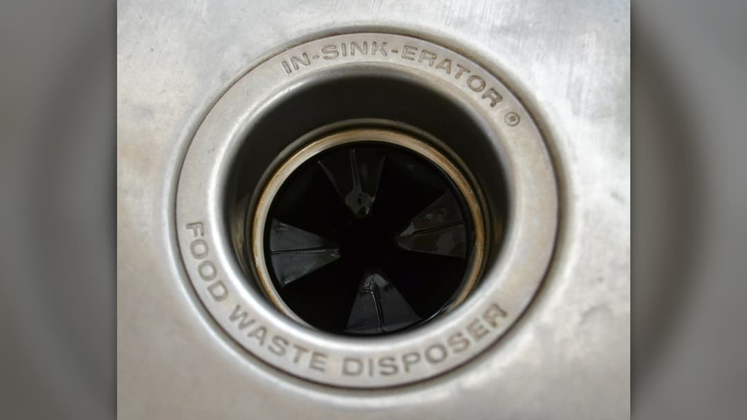 Top-down view into an in-sink garbage disposal drain showing internal blades