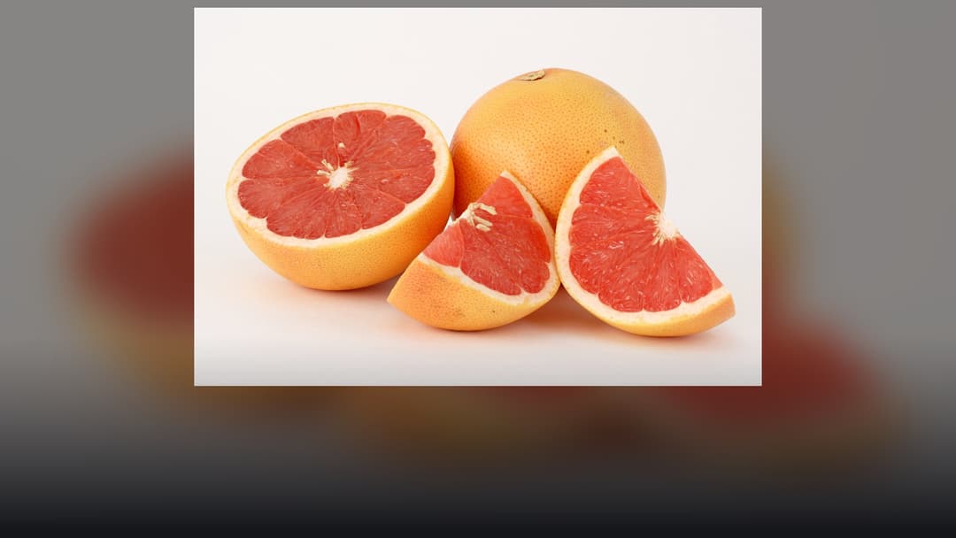 Cross-section of a fresh ruby red grapefruit showing juicy pink citrus segments.