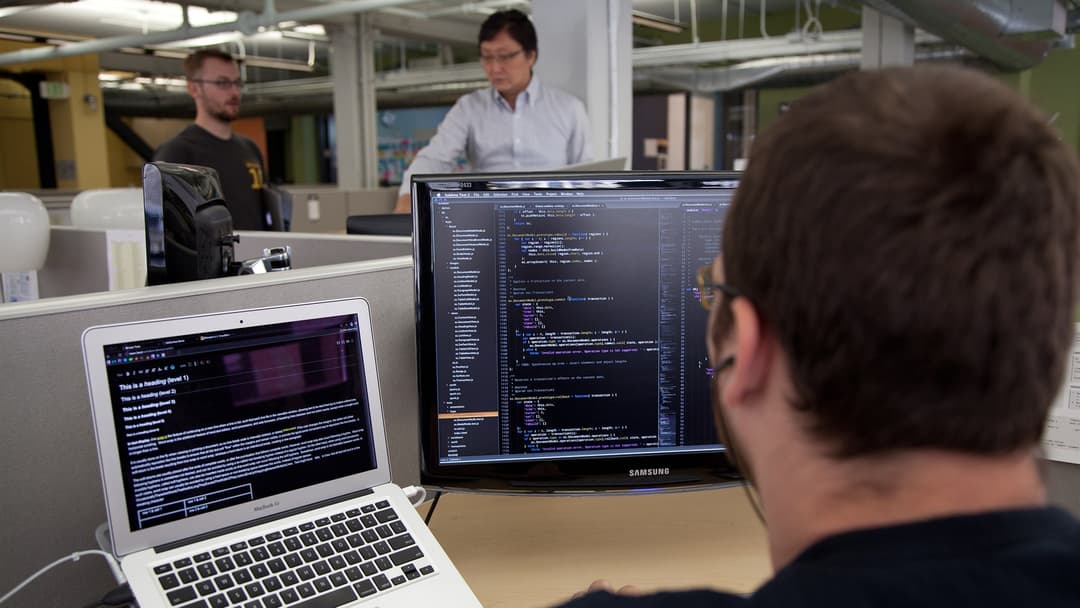 Software architect writing production code across dual monitors in an engineering office
