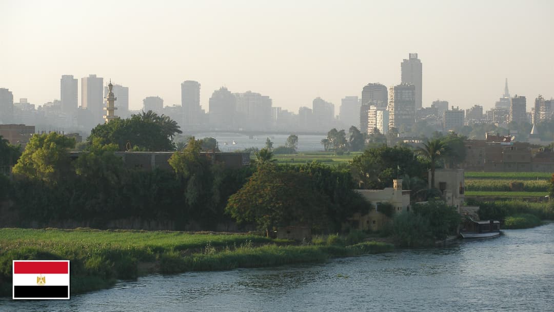 Cairo skyline along the Nile River in Egypt with the Egyptian flag in the bottom left corner