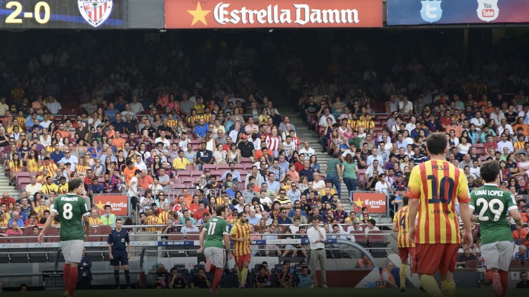 Lionel Messi striking the ball during a competitive match under the floodlights at Camp Nou.