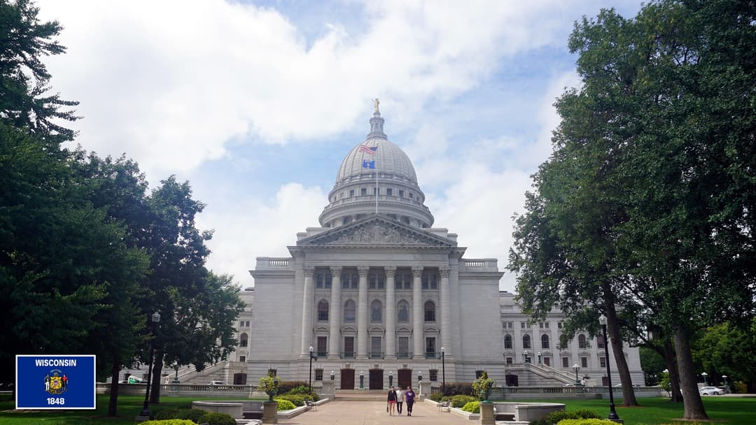 Wisconsin State Capitol in Madison, Wisconsin with the Wisconsin state flag in the bottom left corner