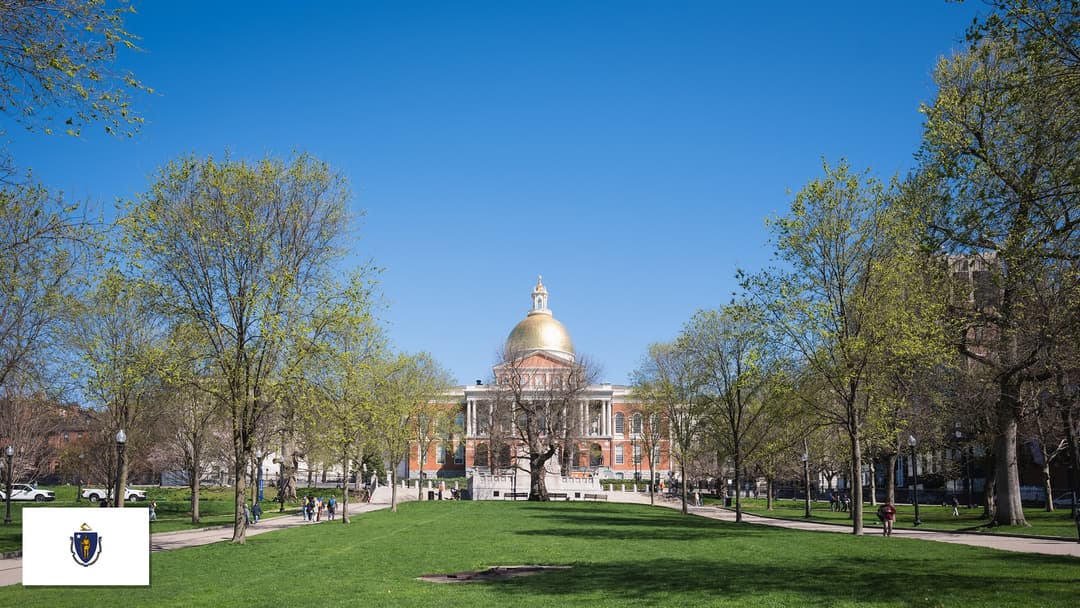 Massachusetts State House overlooking Boston Common in Boston, Massachusetts with the Massachusetts state flag in the bottom left corner