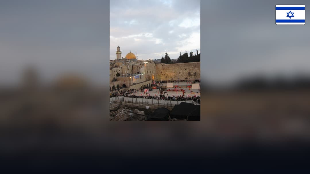 Western Wall and Dome of the Rock in Jerusalem with the Israeli flag in the top right corner.