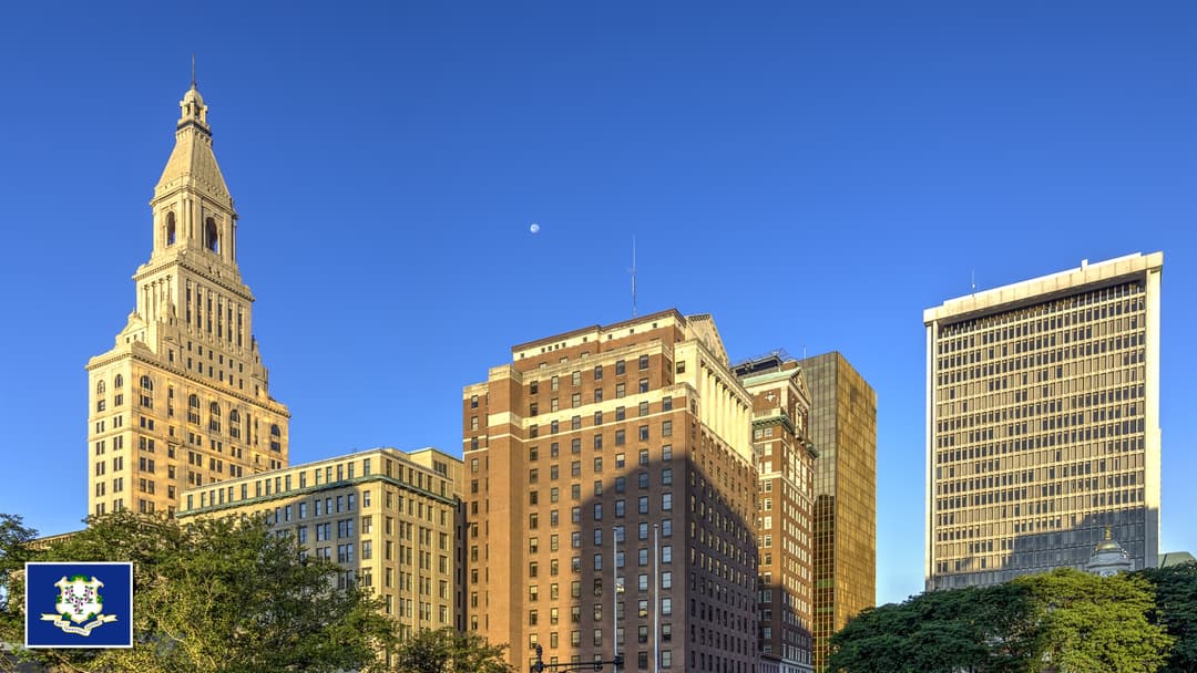 Connecticut State Capitol and Bushnell Park in Hartford, Connecticut with the Connecticut state flag in the bottom left corner