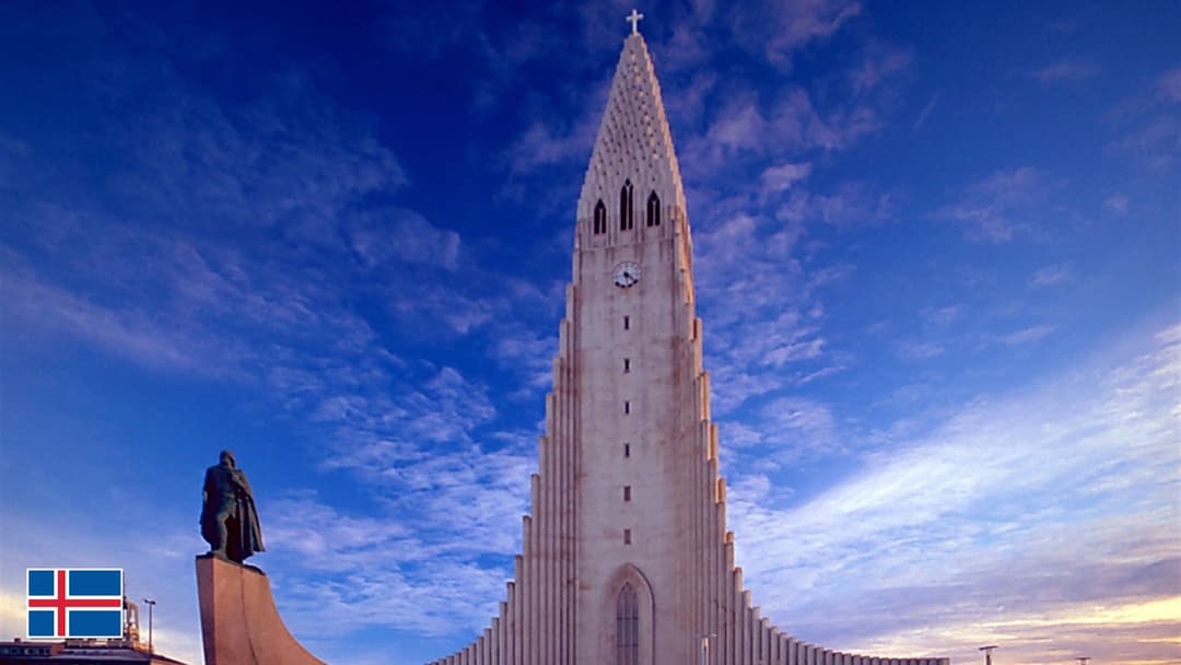 Hallgrimskirkja stepped concrete spire in Reykjavik with flag of Iceland in bottom-left corner