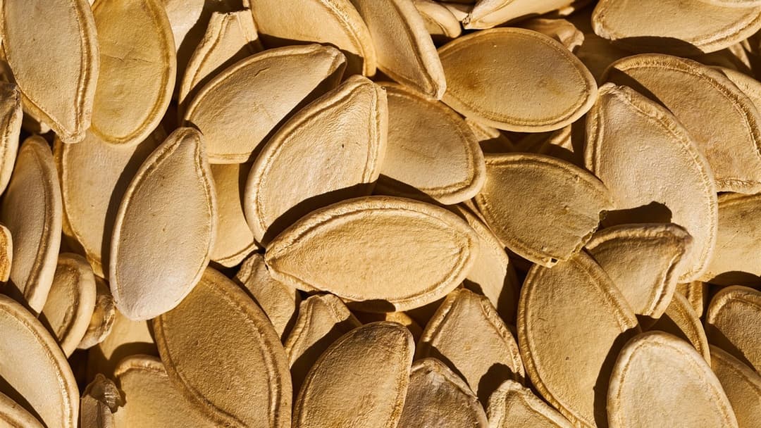 Close-up of roasted whole pumpkin seeds piled together as a nutritious snack.