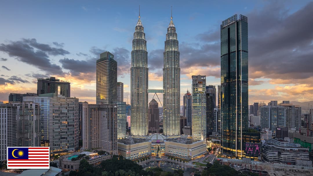 Petronas Twin Towers at sunset in Kuala Lumpur, Malaysia with the Malaysian flag in the bottom left corner