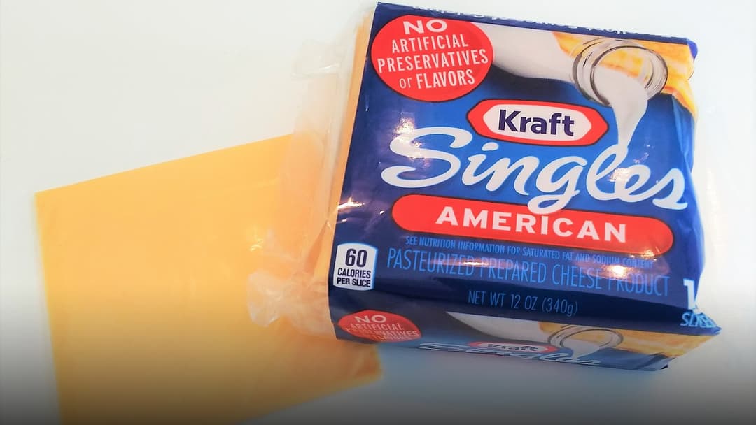 An individually wrapped yellow slice of American pasteurized processed cheese.