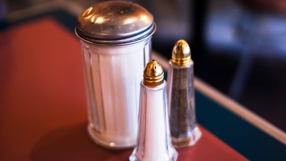 Glass salt and pepper shakers with spilled table salt