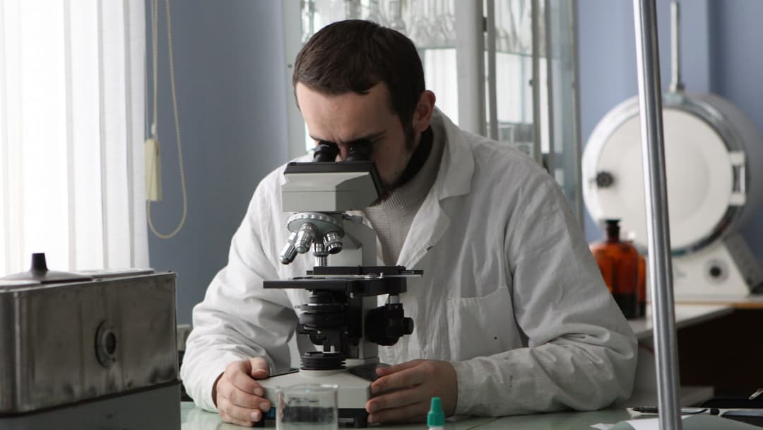A microbiology researcher examining laboratory cultures and assays.