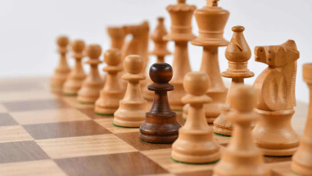 Carved wooden Staunton chess pieces aligned across a checkered board