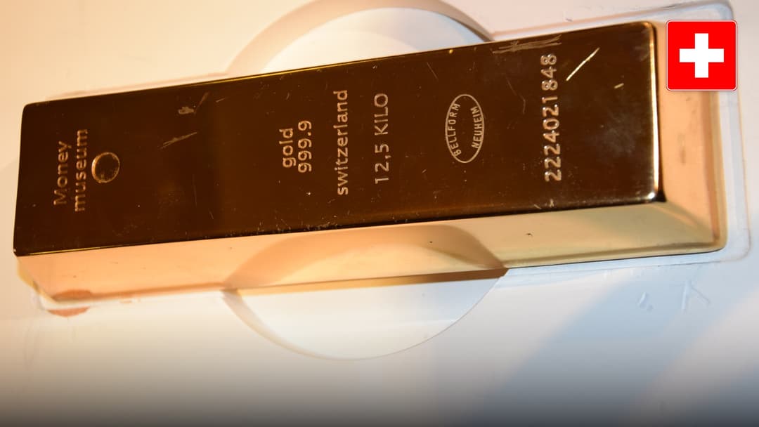 A 400-ounce 999.9 fine Swiss gold bullion bar stamped with refiner hallmarks at the Swiss Money Museum in Zurich. Official national flag badge in top right.