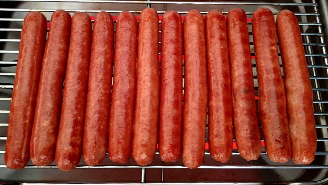 Hot dogs grilling over flame grates