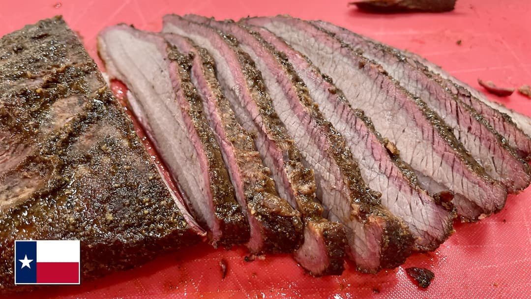 Slices of smoked Texas beef brisket displaying a deep pink smoke ring and peppery bark with Texas flag overlay in bottom-left corner