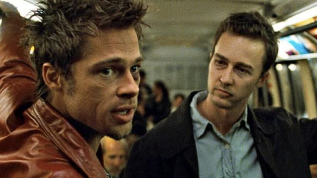 Tyler Durden in a red leather jacket speaking closely with the bruised narrator on a transit car, image horizontally flipped.